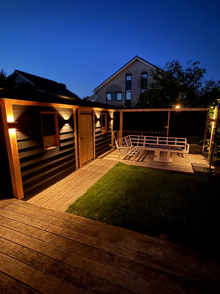 Tuinconstructie schuur en steiger met sfeerverlichting avond